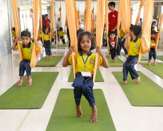 Children practising in aerial yoga hammocks during a Kid’s Yoga session