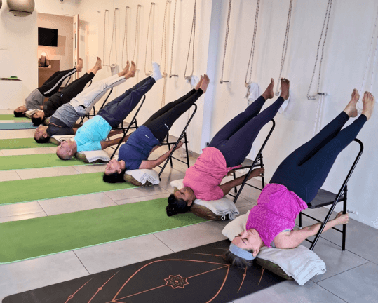 Chair-supported shoulderstand practised along the studio wall
