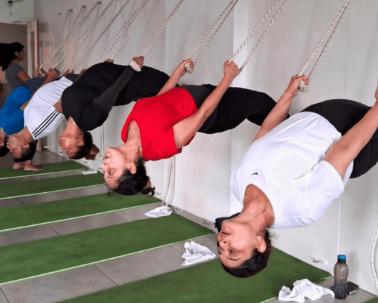 Students opening into a supported backbend on the ropes