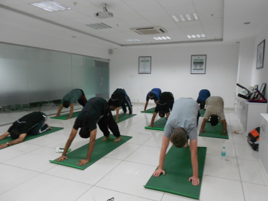 Corporate Yoga session in Adho Mukha Svanasana at an office workspace
